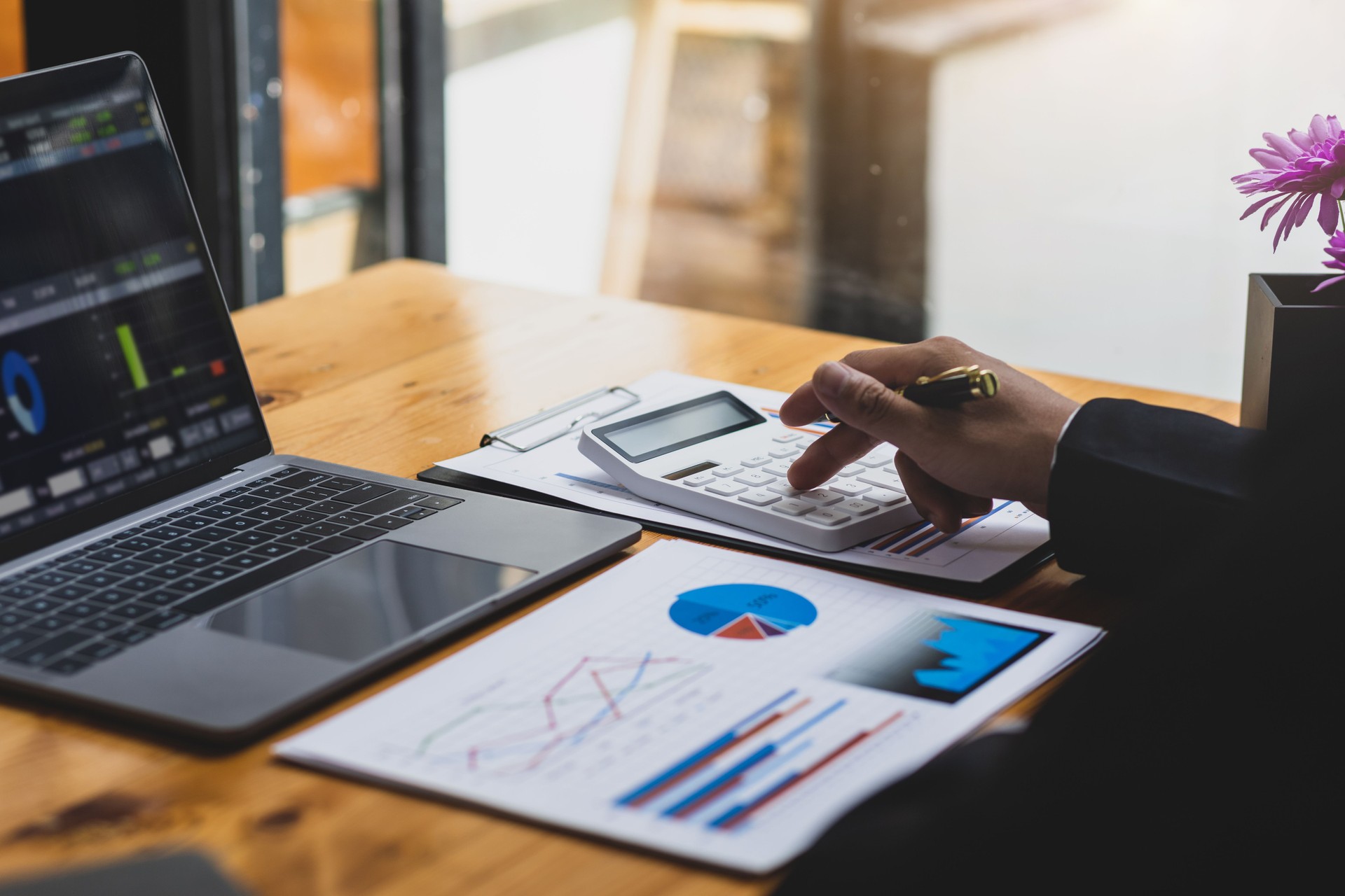 Business people use calculator to analyze financial charts in business reports and budget management. Financial planning and accounting concepts.