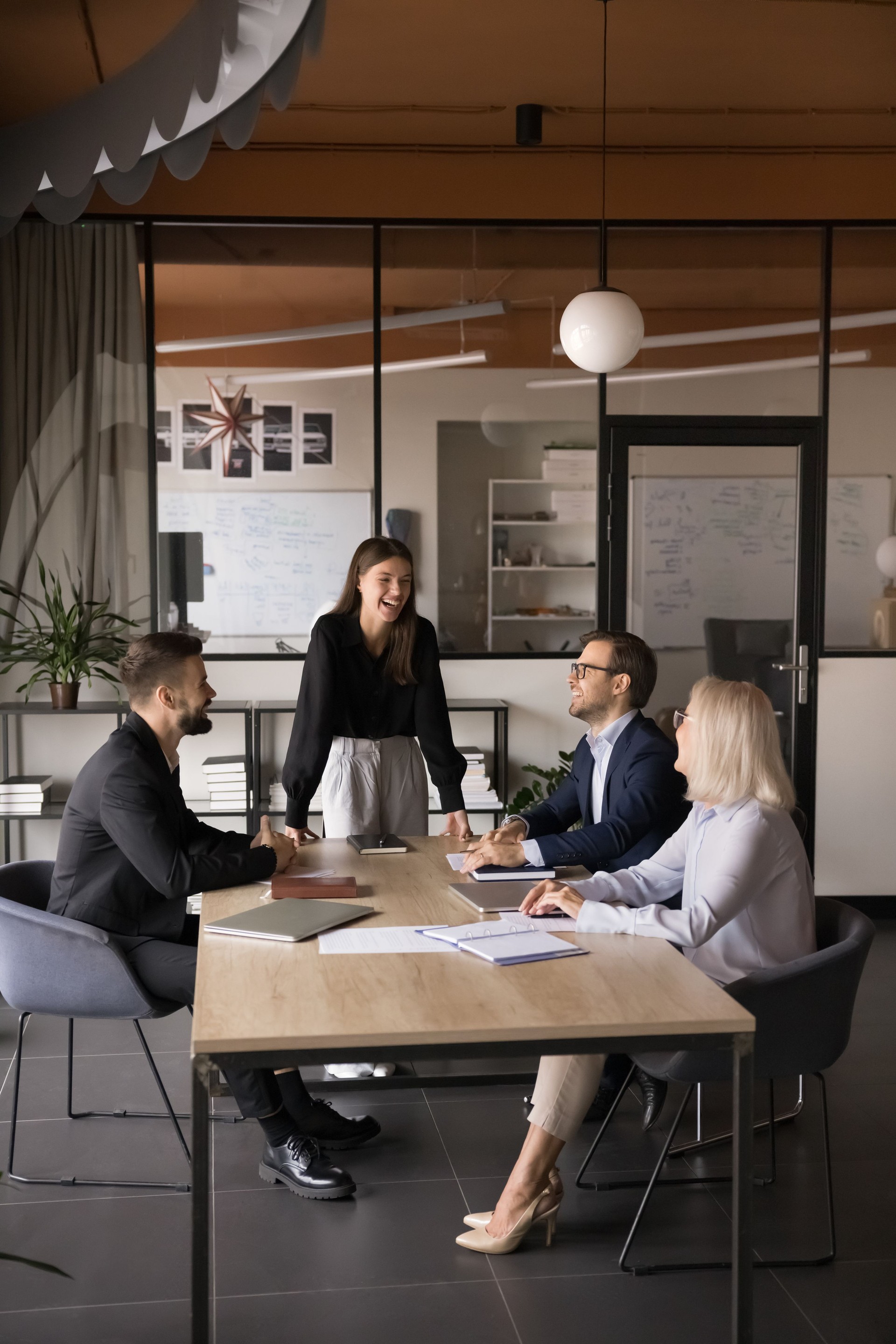 Businesspeople laughing, joking seated around table during presentation